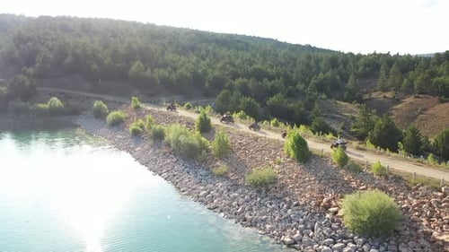 Groupe de personnes à bord d'un véhicule quadricycle tout terrain sur une route forestière au bord du lac 2