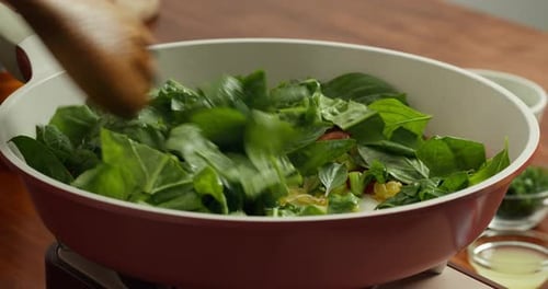 Concept Home Cuisine et inspiration culinaire Les tomates sont frites avec des feuilles d'épinards verts dans un