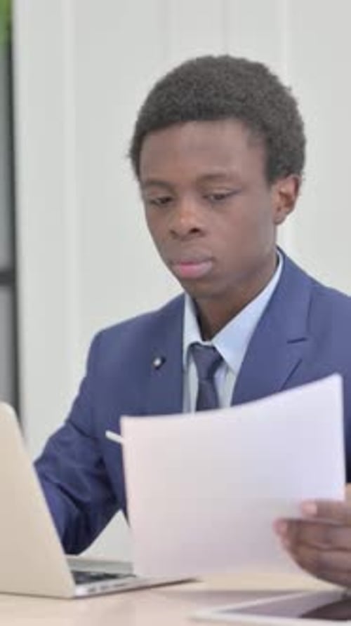 Man in Suit Analyzing Documents at Office Desk
