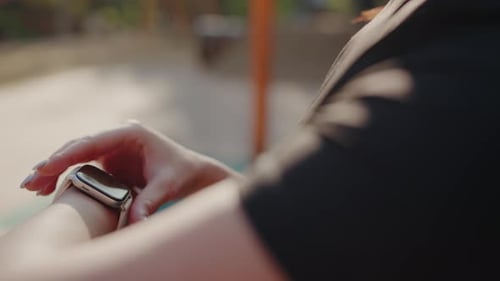 Woman Taps Smartwatch Screen Outdoors