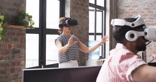 Young Caucasian woman and Asian man, wearing VR headsets as part of a business exploration