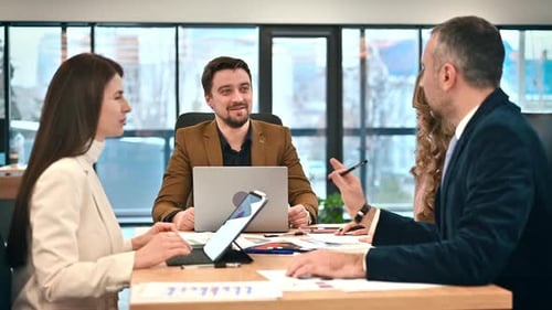 Business meeting in an office, workers discussing business affairs. Gadgets and papers on the table.