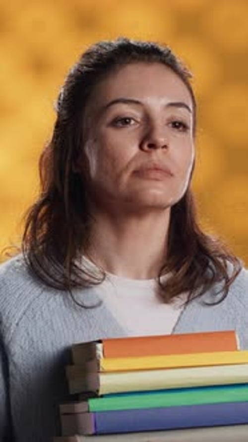 Vertical Video Portrait of Upbeat Woman Holding Pile of Books Studio Background
