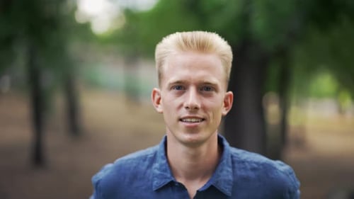 Close Up Portrait Young Happy Blond Man Standing in Nature Between Park Trees Relaxes Breathes Fresh