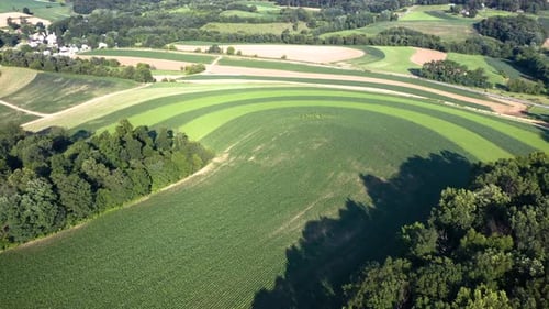 aerial flight over farms tilts down to beautiful curved patterns in the crops