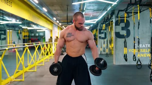 Muscular Man Doing Arm Curls at Bright Gym