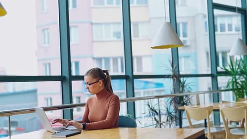 Focused woman etrepreneur typing on laptop. Young female using computer while sitting at home desk.