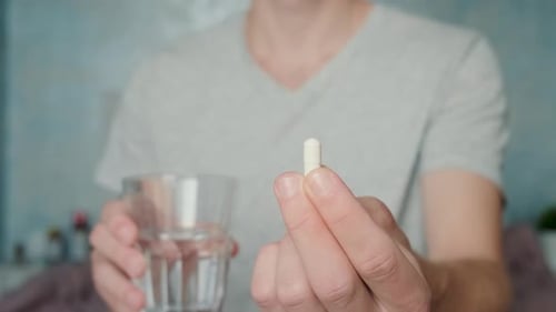 Adult Holds Pill with Water Close Up