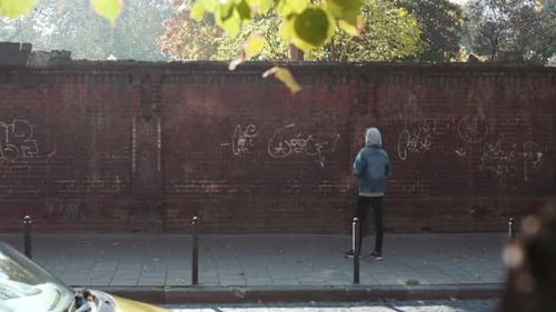 Paris, Frankreich, 5. April 2018 — Rückansicht eines jungen Graffiti-Malers im lässigen Outfit, der seine Arbeit betrachtet