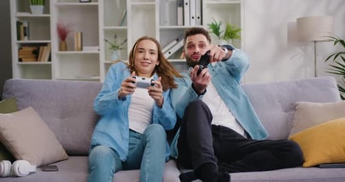 Excited Couple Playing Video Games on Sofa at Home