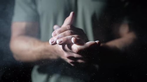 Male athlete clapping hands strongly with magnesium carbonate chalk, Close up slow motion shot