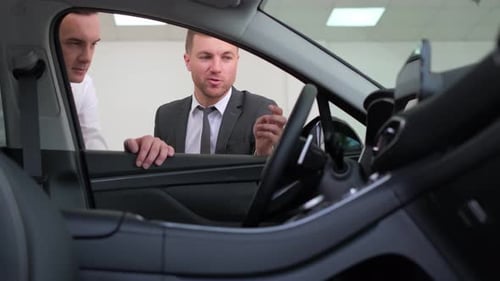 Two Men are Looking at a Car in a Showroom