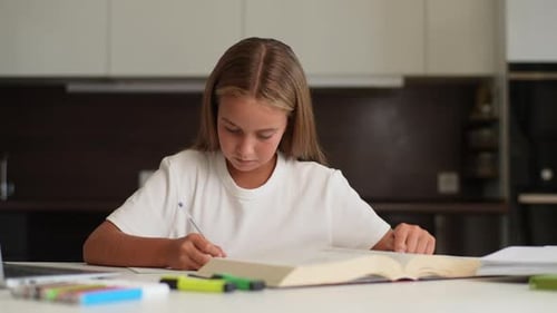 Portrait of Focused Schoolgirl Student Doing Homework Reading Book and Writing in Copybook with
