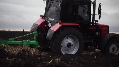 Red tractor plowing the field in Ukraine