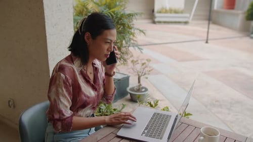 Young Businesswoman Consulting on Smartphone at Cafe Terrace