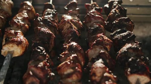 Primer plano de shish kebabs asando a la parrilla a fuego abierto al aire libre. Brochetas de ternera que se están cocinando