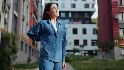 Woman Holding Lower Back in Pain Outdoors
