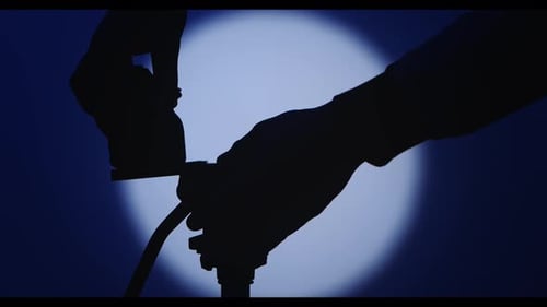 Camera Assembly on Tripod Silhouette Against a Spotlight
