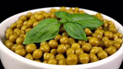 Marinated pickled sweet green peas with white bowl rotate background.
