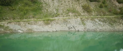 Horizontal Shot of Quarry Lake with Turquoise Water and Rocks with Green Bushes Mountainous Terrain