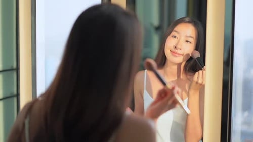 Woman Applies Makeup in Mirror, Bright Room