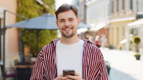 Smiling Man Using Phone on City Street