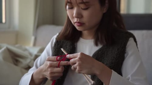 Woman Knitting with Red Yarn in Cozy Home
