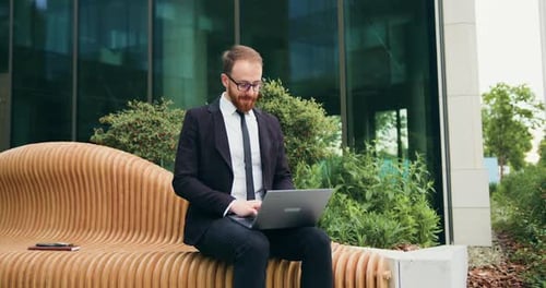Bearded Businessman Working on Laptop Outdoors