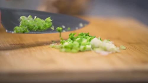 Sliding the cut green onions to the side.