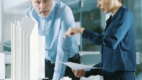 Male Senior Engineer and Female Architectural Designer Work on a Building Model Design for the Urba