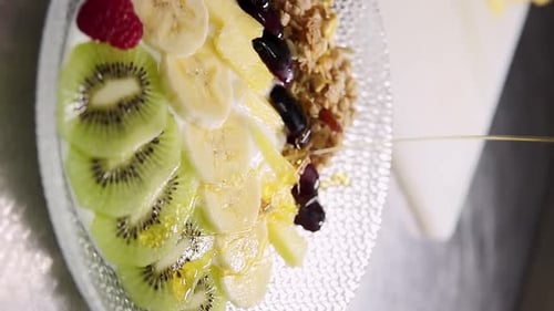 Vertical view of delicious honey syrup poured over healthy breakfast fruit plate
