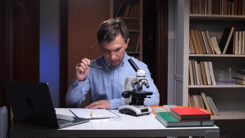 Young Adult With Microscope and Laptop Indoors