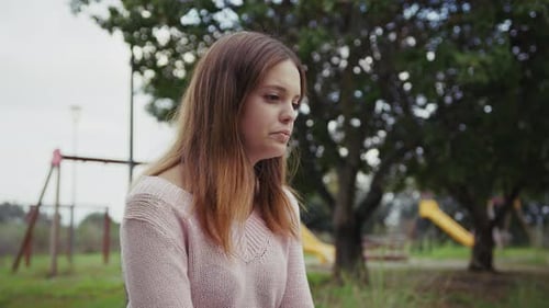 Sad And Lonely Girl Sitting In Park Bench Outdoors