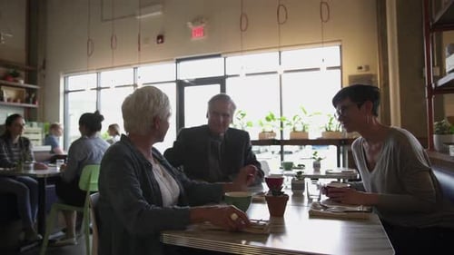 Daughter and Senior Parents Talking and Drinking Coffee in Cafe 4549 Years