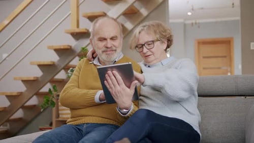 Senior Couple Using Tablet at Home on Couch