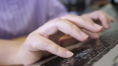 Young adult woman working on laptop computer in cafe