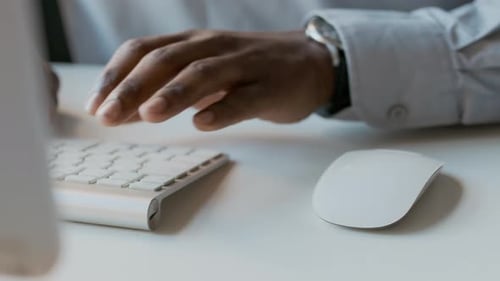 Hands of Black Male Office Worker Using Computer Keyboard and Mouse