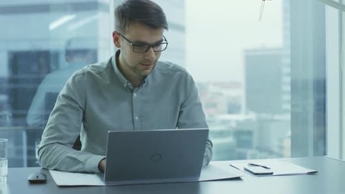 Successful Young Businessman Works on a Laptop in His Modern Office. Smart Young Man Working for a