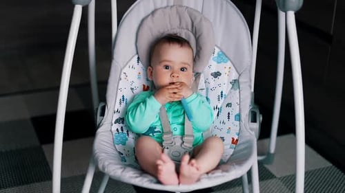 Infant Sits in Baby Swing Chewing on Toy