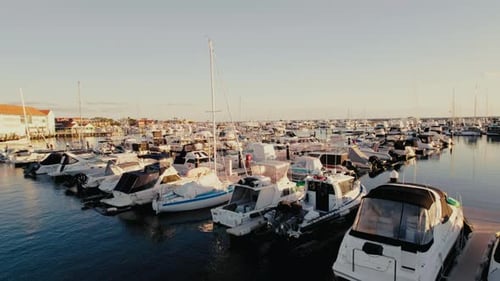 Boats docked at a marina during sunset in a coastal town