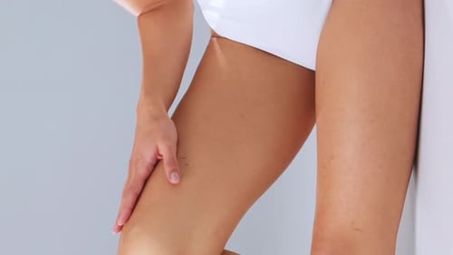 Woman Massages Thigh in Minimalist Studio