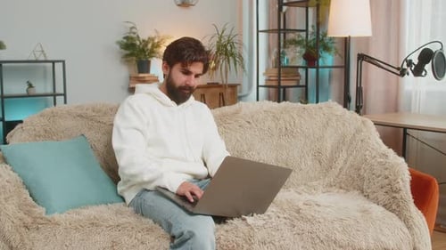 Young Adult Using Laptop on Couch at Home
