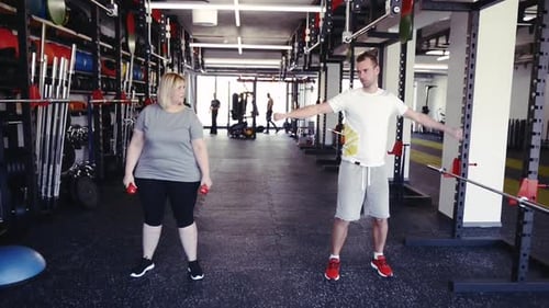 Overweight Woman in Modern Gym Working Out with Dumbbells