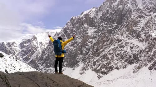 Mountaineer Celebrating Reaching Mountain Peak Raising Arms in Snowy Mountain Landscape