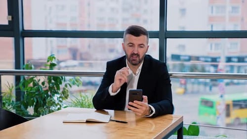 Man Checks Smartphone at Table in Modern Office