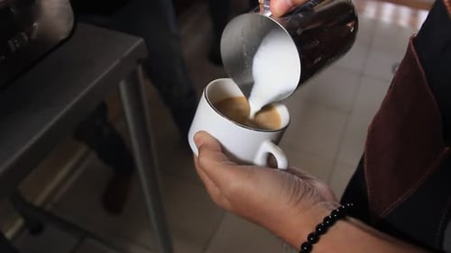 Close up of a barista's hand making a coffee latte. professional coffee making process