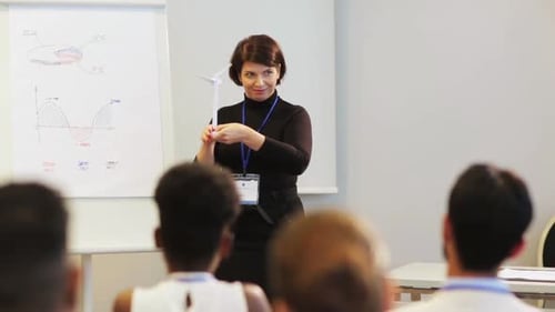 Woman Presenting Wind Turbine Model in Conference Setting