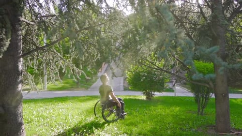 Disabled young man sitting in his wheelchair in nature in slow motion.