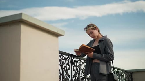 Young Woman Reading a Book Outdoors on Bright Day