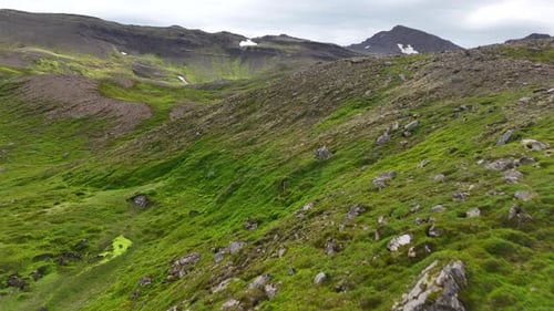 Aerial view of rugged mountains and cliffs in Fjallabyggð, showing rocky slopes, patches of bright
